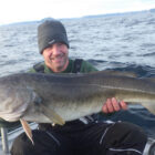 Angler on a boat holding a cod