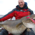 Angler on a boat holding a large cod