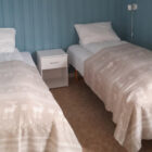 Bedroom with blue striped wallpaper and two single beds either side of white bedside cabinet