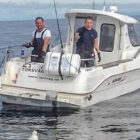 Two anglers fishing from a boat on calm Norwegian fjord
