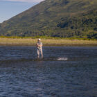 Lady fly fishing in a river in Alaska