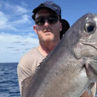 Close up of angler stood behind a bass fish