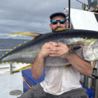Angler sitting on a boat at sea holding a yellow fin tuna