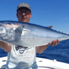 Angler holding a large tuna fish on a boat in open ocean