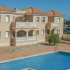 Two storey cream painted holiday villas with balconies and a shared swimming pool