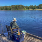 Angler sat on a wooden jetty fishing a lake in Sweden