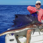 Angler sat on a boat holding a sailfish