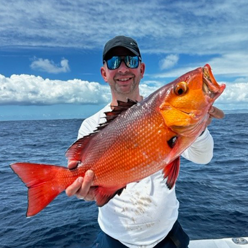 Angler holding a coral trout fish