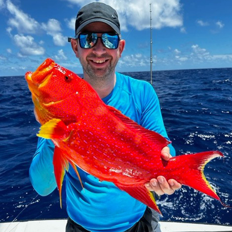A man holding a large vibrat red and orange coral trout