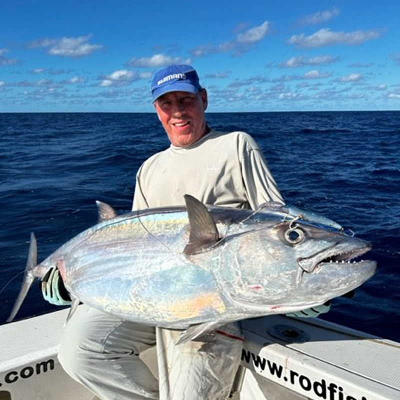 A man holding a large silver dogtooth tuna