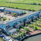 Aerial view of a blue, multi-unit waterfront apartment building with private docks and small boats.