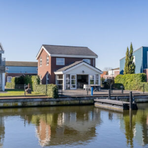Modern brick and blue-sided waterfront villas with private docks along a calm canal.
