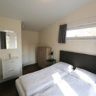 Bright bedroom in a lodge featuring two single beds pushed together and an ensuite vanity sink.