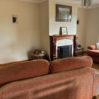 Cosy living room featuring a traditional wooden mantelpiece, fireplace, and peach sofas.