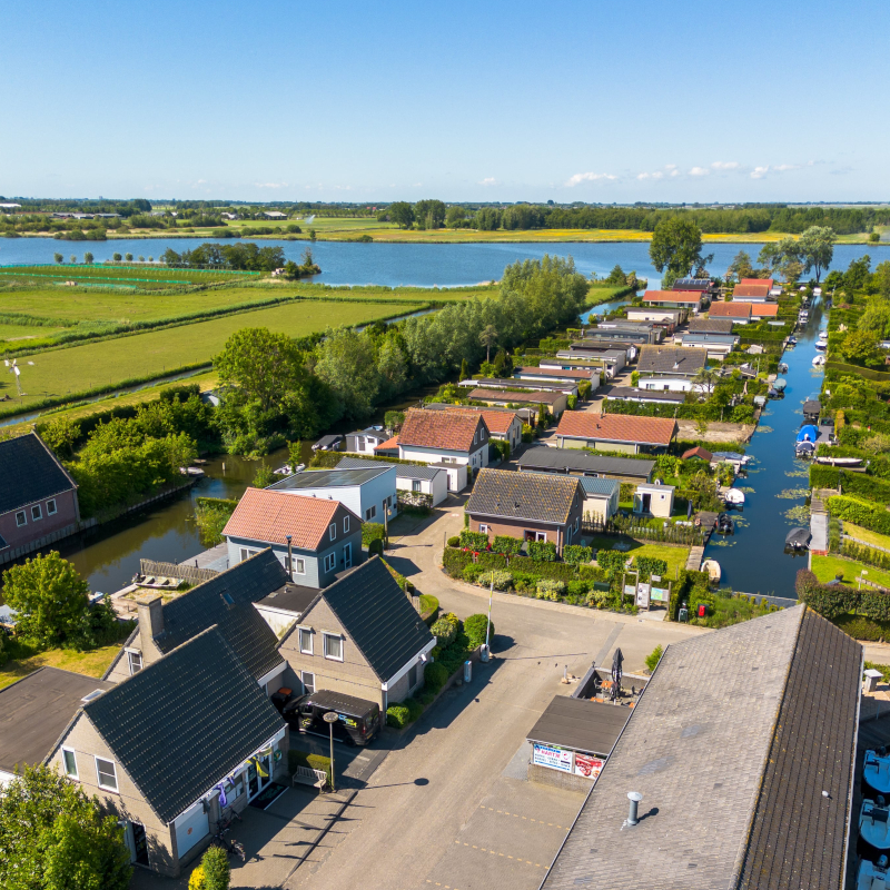 High-angle aerial view of the holiday park entrance road, surrounding chalets, and canals.