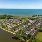 Aerial view of a holiday park village set along waterways near a large open body of water.