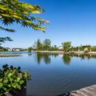 Calm fishing lake on a clear sunny day with holiday chalets visible along the shore.